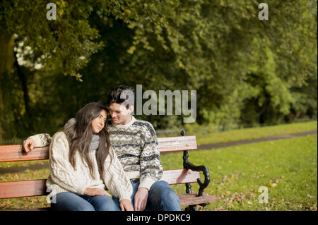 Junges Paar sitzt auf der Parkbank Stockfoto