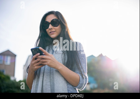 Junge Frau mit Sonnenbrille mit smartphone Stockfoto