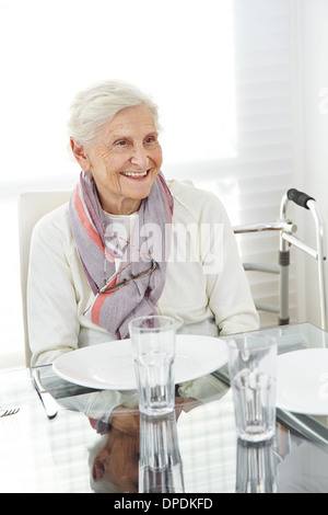 Glückliche senior Frau sitzen am gedeckten Tisch für das Mittagessen Stockfoto
