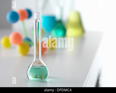 Becher mit Lösung von chemischen Experiment mit molekularen Modell im Hintergrund am Labortisch Stockfoto