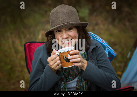 Reife Frau sitzen auf Campingstuhl, heißes Getränk trinken Stockfoto