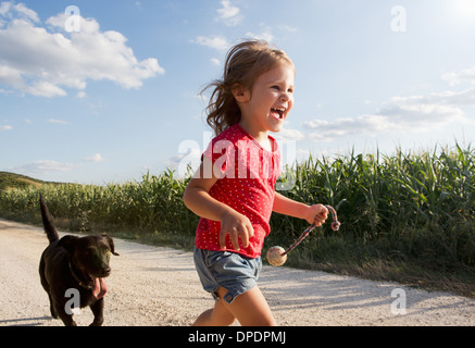 Mädchen und Hund läuft durch Feld Stockfoto