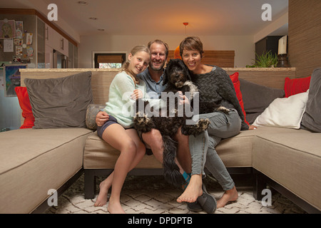 Porträt von Eltern, Tochter und Hund auf sofa Stockfoto