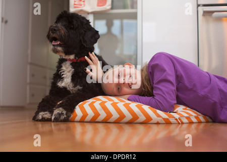 Porträt eines Mädchens auf Kissen liegend mit Hund Stockfoto