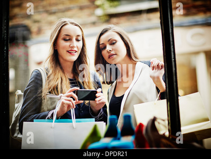 Junge Frauen Fenster einkaufen, Fotografieren mit smartphone Stockfoto