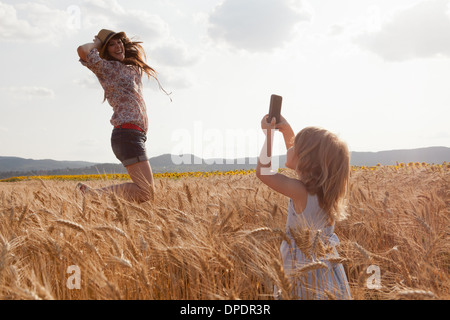 Mädchen nehmen Foto von Mutter im Weizen Feld springen Stockfoto