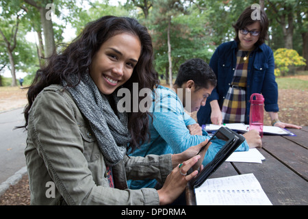 Studenten sitzen am Tisch im Park Hausaufgaben Stockfoto