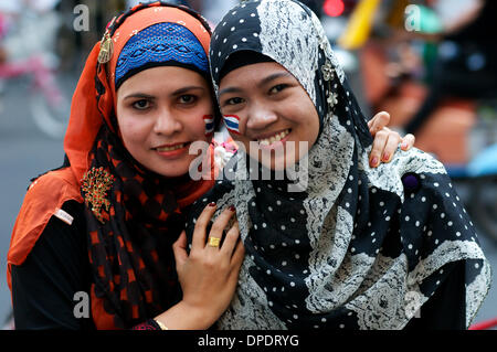 Bangkok, Thailand. 13. Januar 2014. Zwei, sehr feminin, muslimische Frauen, protestieren in Harmonie, w / Thai Fahnen gemalt auf ihren Gesichtern, im Publikum einer großen Protest der Anti-Regierungs-Bewegung. Viele der Demonstranten kommen aus Süd-Thailand, einer großen muslimischen Bevölkerung. In einer versuchten Herunterfahren von Bangkok gingen zehntausende von Demonstranten auf die Straße um den Rücktritt von Ministerpräsident Thailands Yingluck Shinawatra fordern. "Herunterfahren Bangkok". Bildnachweis: Kraig Lieb / Alamy Live News benutzerdefinierte Bräuche lebendig Aktivist Aktivisten expressiven Ausdruck Ausdrücke eindrucksvollen Stockfoto