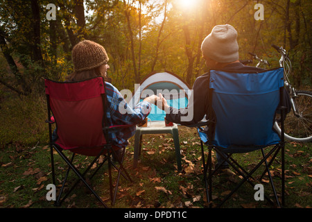 Älteres paar sitzen auf camping Stühle draußen Zelt, Hand in Hand Stockfoto