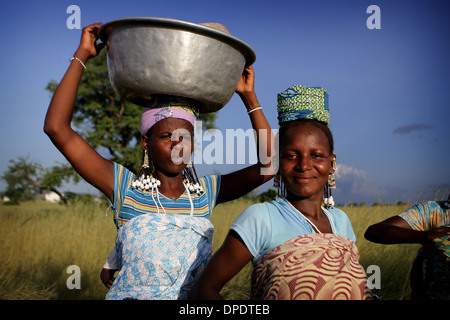 Afrikanische Frauen auf dem Weg zum Markt mit Produkten, die in Körbe, Becken und Säcke durchgeführt Stockfoto