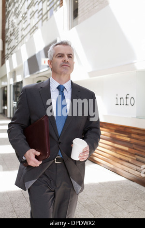 Geschäftsmann zu Fuß hinunter Korridor im Büro Stockfoto