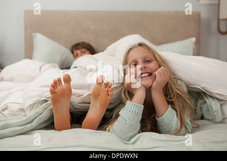 Porträt eines Mädchens auf Bett liegend mit Mütter Füße Stockfoto