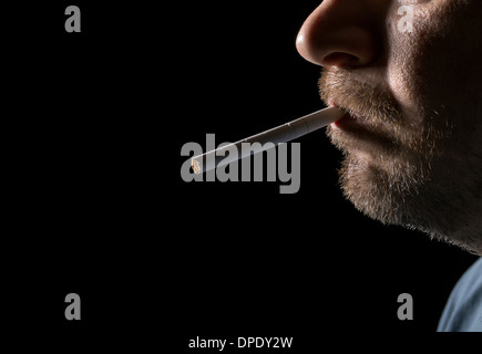 Portrait Mann rauchen Zigaretten, Closeup auf schwarzem Hintergrund Stockfoto