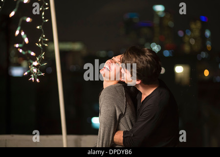 Junges Paar umarmt auf Party auf dem Dach Stockfoto