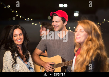 Junge Erwachsene Freunde genießen Gitarrenmusik auf Party auf dem Dach Stockfoto