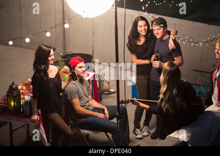 Junge Erwachsene Freunde anhören von Gitarre auf Party auf dem Dach Stockfoto