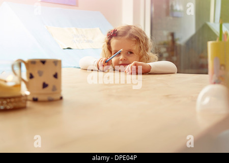 Porträt von weiblichen Kleinkind stützte sich auf Küchentisch Stockfoto