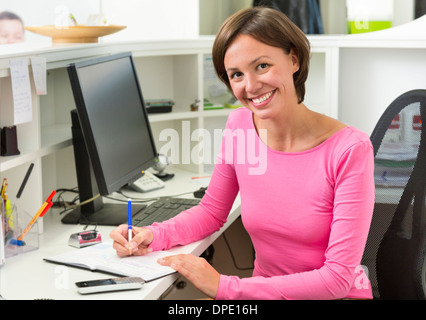 Empfangsdame schreiben am Schreibtisch Stockfoto
