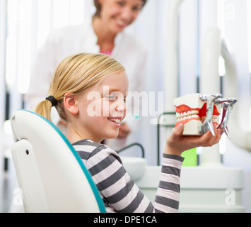 Mädchen in Zahnärzte Stuhl halten Sie falsche Zähne Stockfoto