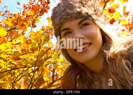 Junge Frau im Pelzhut im herbstlichen park Stockfoto