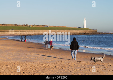 Menschen, die Hunden spazieren entlang des Strandes in Whitley Bay mit Str. Marys Insel in den Hintergrund-Nord-Ost England UK Stockfoto