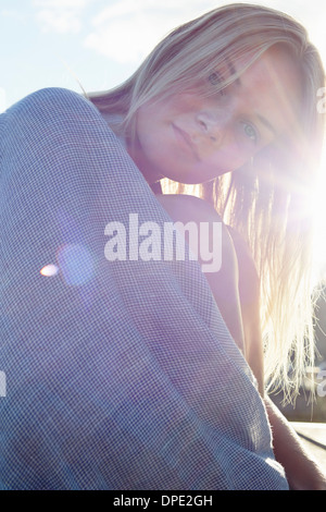 Junge Frau eingewickelt in eine Decke in der Sonne Stockfoto