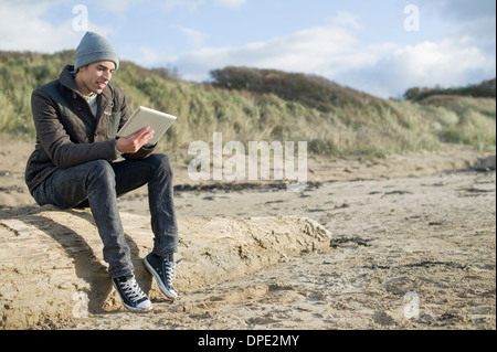 Junger Mann mit digital-Tablette, Brean Sands, Somerset, England Stockfoto