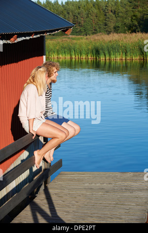 Junges Paar sitzt neben See, Hotels, Schweden Stockfoto