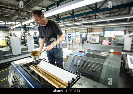 Arbeiter, die Druckmaschine in Druckwerkstatt Goldtinte zuweisen Stockfoto