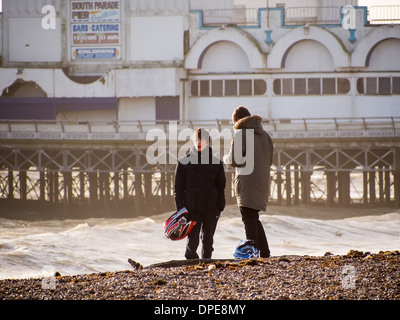 Zwei junge Männer in Parkers stehen am Strand vor Southsea Pier mit Motorradhelme. Stockfoto