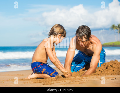 Vater und Sohn spielen zusammen im Sand am tropischen Strand, Gebäude Sand castle Stockfoto