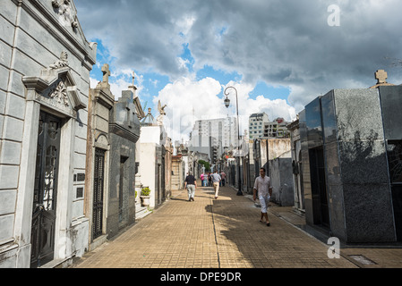 BUENOS AIRES, Argentinien – Ein Pfad auf dem Friedhof Recoleta (Cementerio de la Recoleta) zeigt das städtische Layout des Friedhofs. Diese Fußgängerkorridore, die die Straßen der Stadt nachahmen, bilden ein organisiertes Gitter zwischen den kunstvollen Mausoleen und Gräbern. Die rationelle Planung des Friedhofs spiegelt den europäischen Einfluss auf die argentinische Stadtgestaltung des 19. Jahrhunderts wider. Stockfoto