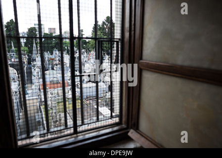 BUENOS AIRES, Argentinien – Ein Blick durch eines der ursprünglichen Fenster aus der Kolonialzeit auf die Basílica de Nuestra Señora del Pilar offenbart den historischen Friedhof Recoleta dahinter. Der 1822 errichtete Friedhof befindet sich neben der Kirche von 1732 und zählt zu den bedeutendsten historischen Stätten von Buenos Aires. Die architektonische Beziehung zwischen diesen beiden historischen Wahrzeichen veranschaulicht die historische Bedeutung des Stadtteils Recoleta. Stockfoto