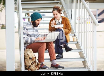 Hipster-paar mit Computer und sitzen in Treppe am Campus der Universität Essen Stockfoto