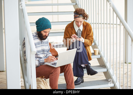 Hipster-paar mit Computer und Smartphone am Uni-campus Stockfoto