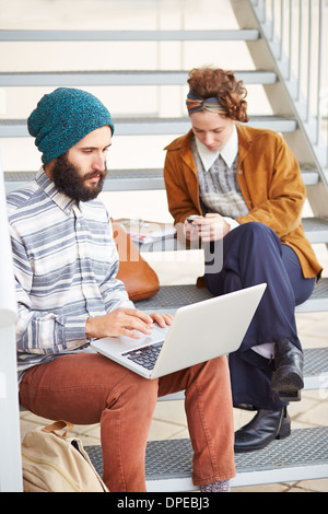 Hipster-paar mit Computer und Smartphone am Uni-campus Stockfoto