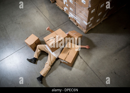 Mann am Boden liegend fallenden Kartons im Lager Stockfoto