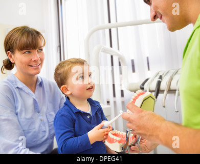 Junge Mütter Schoß beizubringen, wie man Zähne putzen Zahnarzt Stockfoto