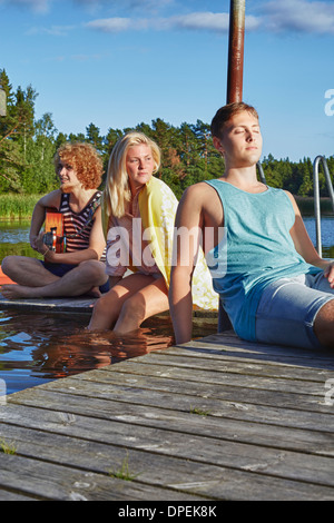 Drei junge Erwachsene Freunde entspannend auf Pier, Hotels, Schweden Stockfoto