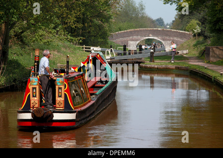 Eine traditionelle Arbeiten Narrowboat nähert sich Lock 6 von den Audlem Flug von Sperren auf dem Shropshire-Union-Kanal Stockfoto