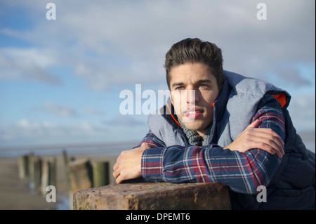 Junger Mann stützte sich auf der Buhne, Brean Sands, Somerset, England Stockfoto