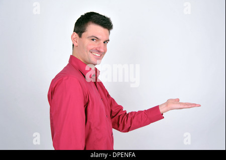 ein schöner europäischen braunen Mann lächelnd und zeigt Exemplar mit seiner Hand und zeigt eine Werbebotschaft Stockfoto