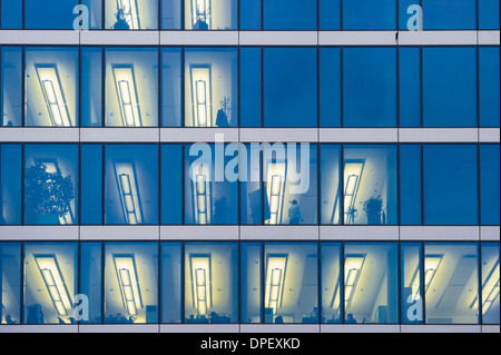 Fassade eines modernen Bürogebäudes mit Licht in den Büros am Abend, München, Bayern, Deutschland Stockfoto