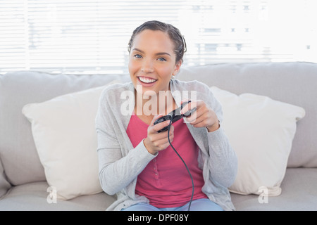 Glückliche Frau sitzt auf dem Sofa spielen von Videospielen Stockfoto