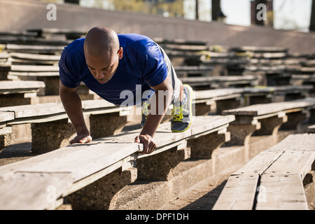 Mann tut Push ups auf Bank Stockfoto