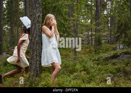 Mädchen im Teenageralter spielen Versteckspiel im Wald Stockfoto