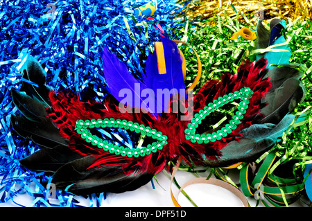 Karnevalsmaske mit Federn in verschiedenen Farben auf einem Hintergrund mit Lametta in verschiedenen Farben Stockfoto