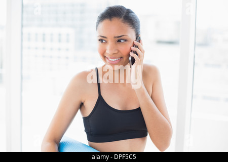 Nachdenklich dunklen Haaren Modell in Sportbekleidung einen Anruf tätigen Stockfoto