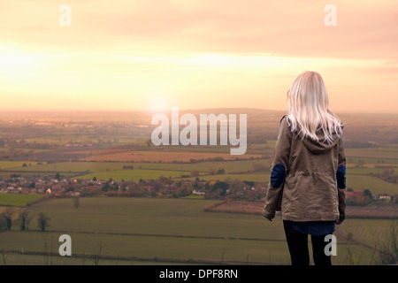 Junge Frau, die gerade Sonnenaufgang über ländliche Landschaft Stockfoto