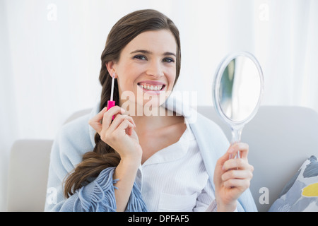 Glücklich lässige braune kurzhaarige Frau in weißen Schlafanzug Anwendung Glanz Stockfoto